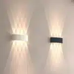 Appliques murales LED noire et blanche avec faisceaux lumineux croisés.