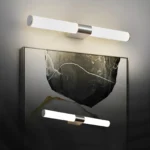Applique murale LED cylindrique moderne installée au-dessus d'un miroir, illuminant un tableau au design abstrait.