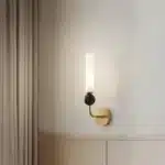 Applique murale dorée avec coude en marbre et cuivre, abat-jour en verre dépoli pour un salon moderne.