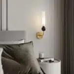 Applique murale dorée avec coude en marbre et cuivre, abat-jour en verre dépoli pour un salon moderne.