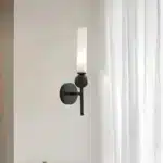 Applique murale noire droite en marbre et cuivre, abat-jour en verre dépoli installée dans un salon moderne.