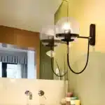 Applique murale nordique moderne en verre avec support noir, installée dans une salle de bain.