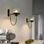 Appliques murales nordiques modernes en verre ambre avec support noir installées dans un couloir.