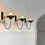 Trio d'appliques murales nordiques modernes avec boules en verre ambre et supports noirs.
