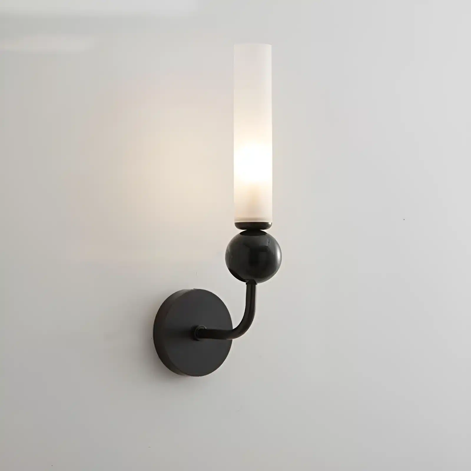 Applique murale noire avec coude en marbre et cuivre, abat-jour en verre dépoli pour un salon élégant.