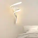 Applique murale LED en forme de tourbillon éclairé pour chambre, blanche, installée près d'un lit.