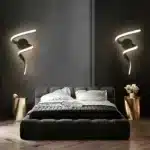 Deux appliques murales LED en forme de tourbillon noir, installées de chaque côté d'un lit dans une chambre contemporaine.