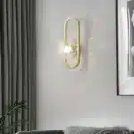Applique murale LED ovale dorée avec abat-jour en verre texturé effet bulle, montée sur un mur de chambre.