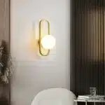 Applique murale LED ovale dorée avec abat-jour lisse, installée dans une chambre moderne.
