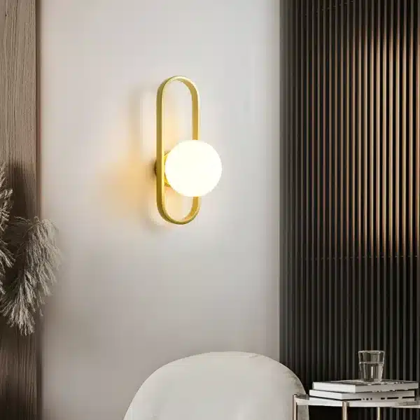 Applique murale LED ovale dorée avec abat-jour lisse, installée dans une chambre moderne.