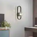 Applique murale LED ovale noire avec abat-jour en verre texturé effet bulle, installée dans un intérieur moderne.