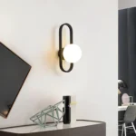 Applique murale LED ovale noire avec abat-jour lisse, installée dans une chambre design.