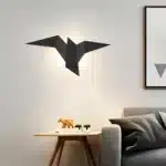 Applique murale noire en forme d'oiseau installée au-dessus d'une table dans un salon.