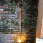 Applique murale rétro en corde de chanvre pour chambre, montée sur un mur en briques avec une lumière chaude.