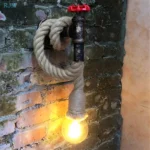 Applique murale rétro en corde de chanvre pour chambre, installée sur un mur de briques.