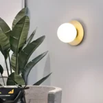 Lampe murale sphérique en noir et or avec un globe lisse doré.