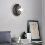 Lampe murale sphérique en noir et or avec un globe en verre texturé noir.