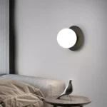 Lampe murale sphérique en noir et or avec un globe lisse noir.