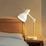 Lampe de chevet blanche moderne sur une table de chevet en bois.