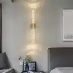Applique murale LED dorée illuminant une chambre avec un design moderne