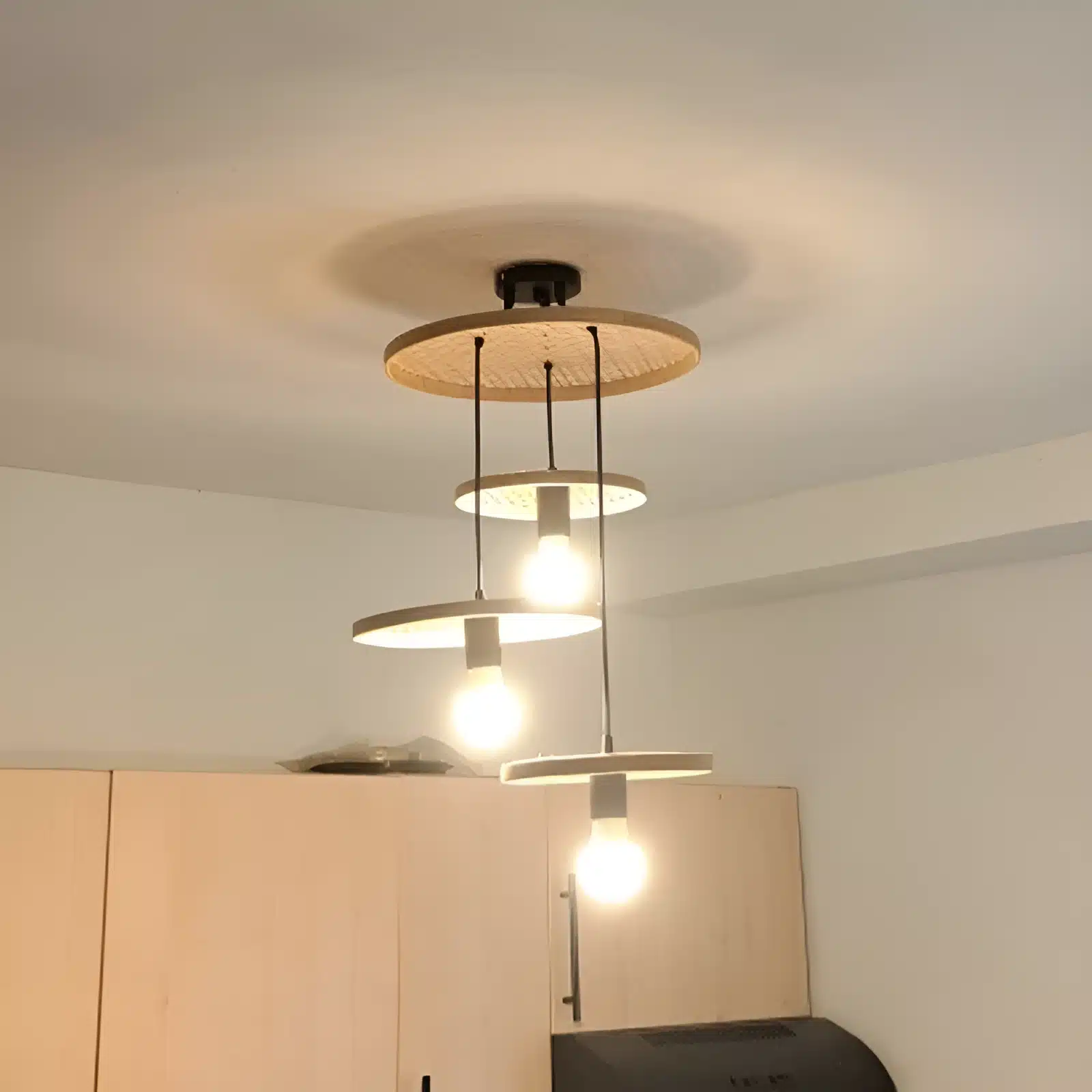 Plafonnier design moderne avec trois ampoules suspendues en cercles en bois.