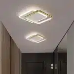 Plafonnier LED carré entrelacé en fer forgé et acrylique doré installé dans un couloir, offrant un éclairage moderne et élégant